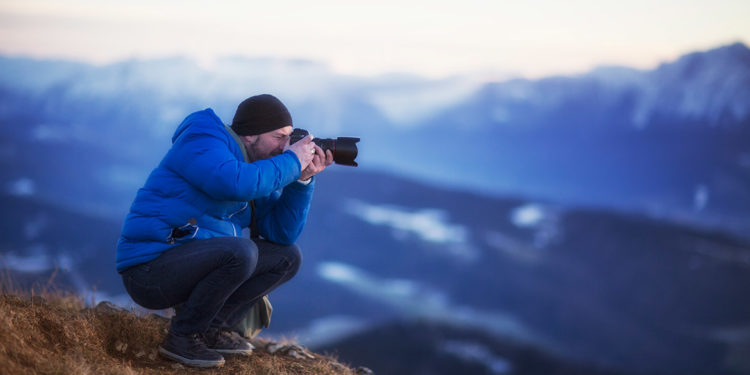 Man Taking Photos Standing On Mountain